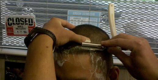 A barber carefully shaping a hairline